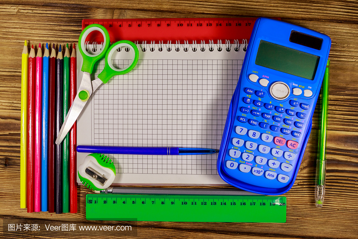 整套學校文具用品。空白記事本,計算器,尺子,鉛筆,鋼筆,剪刀和卷筆刀放在木桌上。俯視圖